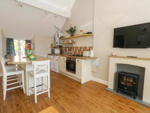 a kitchen with a fireplace and a table and a television at Sea Pink Cottage in Swanage +28 photos