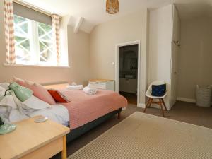 a bedroom with a bed and a window and a chair at Sea Pink Cottage in Swanage