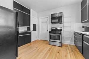a kitchen with stainless steel appliances and wooden floors at 2 BR - Fully Equipped Dearborn Home in Dearborn +13 photos