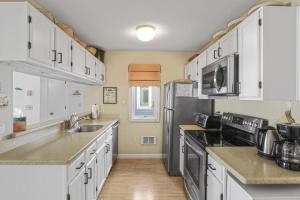 a kitchen with white cabinets and a stainless steel refrigerator at Coastal Cozy in Brewster