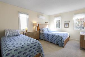 a bedroom with two beds and two windows at Coastal Cozy in Brewster +10 photos