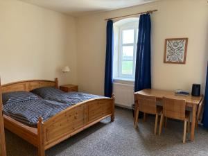 a bedroom with a bed and a desk and a window at Altes Gutshaus Schwiessel in Prebberede