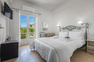 a white bedroom with a large bed and a window at Mimoza in Spetses