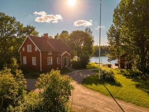 a red house with a lake in the background at Stay North - Mustio in Inkoo