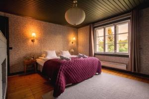 a bedroom with a bed with a purple blanket and a window at Stay North - Mustio in Inkoo