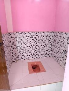 a pink bathroom with a toilet with a pink wall at itynnad homestay in Shillong