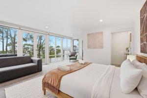 a white bedroom with a large bed and a couch at Bush Escape with Water Views in Tinderbox