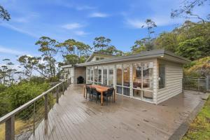 a small house with a wooden deck with a table at Bush Escape with Water Views in Tinderbox