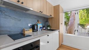 a kitchen with white cabinets and a sink and a window at Absolute Beachfront Studio with Pool and Ocean Views in Palm Cove