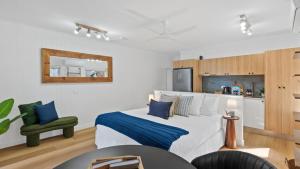 a bedroom with a white bed and a green chair at Absolute Beachfront Studio with Pool and Ocean Views in Palm Cove