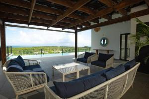 a patio with a couch and chairs and a table at Luxury Oceanview Condo Rooftop Infinity Pool in Las Terrenas