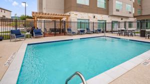 a swimming pool with chairs and tables in a building at Wingate by Wyndham Austin North - Round Rock in Austin