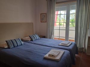 a bedroom with two beds with blue sheets and a window at Praia Del Rei Pool in Amoreira