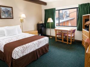 a hotel room with a bed and a desk and a window at Aisling Suites in Great Falls