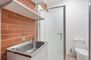 a bathroom with a sink and a brick wall at Stylish West Hobart Villa in West Hobart