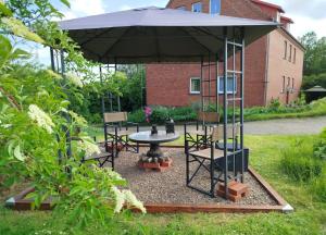 a table and chairs under an umbrella in a garden at Ferienwohnung am Ellerbach in Hessisch Oldendorf