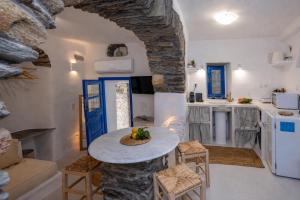a kitchen with a table in a room with a stone wall at Adamma Tinos in Kékhros