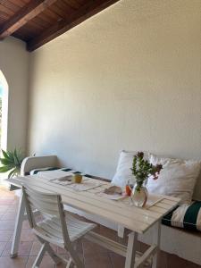 a white table with a vase of flowers on it at Splendida villetta Kal'e Moru in Marongiu
