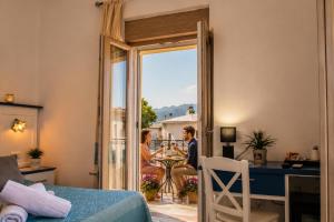 a couple sitting at a table in a living room with a view at INAH Rooms in Dorgali
