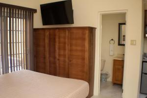 a bedroom with a large wooden cabinet with a flat screen tv at The Vista Inn Studio #1 in Falmouth