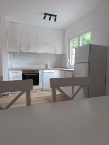 a kitchen with white cabinets and a refrigerator and a table at Zen Zone Trio in Foča
