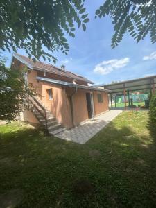 a building with a staircase next to a grass yard at Vikendica na dan in Novi Sad