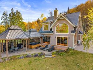 a house with a patio and a grill at Waterfront with VIEW and SPA in Saint-Raymond