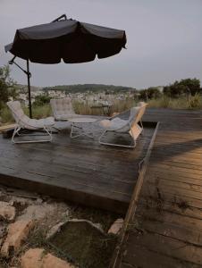 Zwei Stühle und ein Sonnenschirm auf einer Holzterrasse in der Unterkunft Goshen in ‘Isfiyā