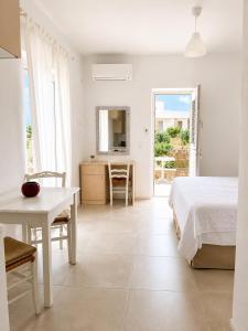 a white bedroom with a bed and a table at Aphrodite's Villa in Ambelas