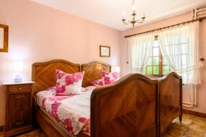 a bedroom with a wooden bed with pink pillows at Gîte Éclat De Soleil in Beblenheim