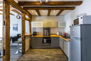 a kitchen with stainless steel appliances and wooden beams at La Curiosité in Barr
