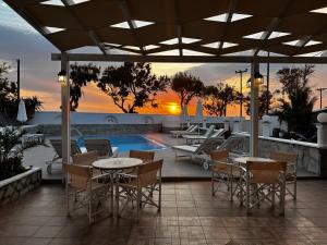 a patio with tables and chairs and a swimming pool at Villa Ilios in Fira