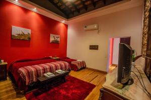 a red room with two beds and a tv at Nido de Pajaros Posada Boutique in Concepción