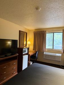 a hotel room with a bed and a desk and a window at LaVale Inn Cumberland Area in La Vale