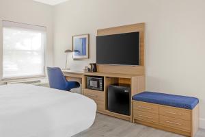 a bedroom with a bed and a tv and a blue chair at Best Western St. Louis Fairview Heights in Fairview Heights
