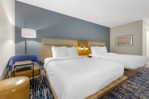 a hotel room with two beds and a chair at Best Western St. Louis Fairview Heights in Fairview Heights