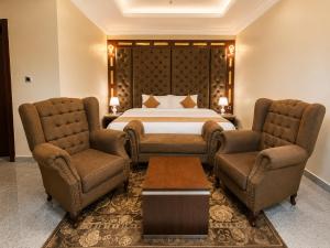 a hotel room with a bed and two chairs at Grand Bohabs Hotel in Abuja