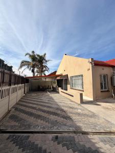 a building with a fence and a palm tree at The Perfect Place in Parow