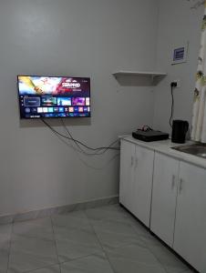 a tv hanging on a wall in a kitchen at Nandyowa Guesthouse in Kampala