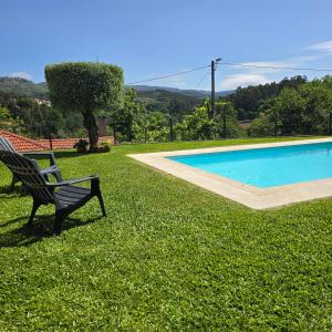 a bench sitting in the grass next to a swimming pool at Casa da Batoca - Rossas in Vieira do Minho
