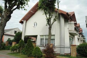 a white house with a fence in front of it at Willa Promyk in Jastarnia