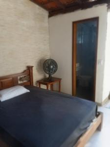 a bedroom with a bed and a fan next to a door at Suites perto praia in Ubatuba