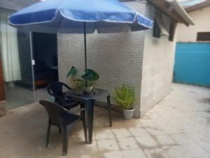 a table with a blue umbrella and a chair at Suites perto praia in Ubatuba