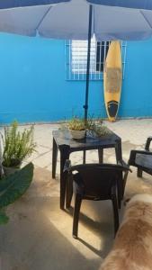 a table and chair with a surfboard on the beach at Suites perto praia in Ubatuba