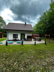 a small white house with a playground in the yard at Domek w lesie Sauna i Gorąca balia Wellness&Spa in Grybów