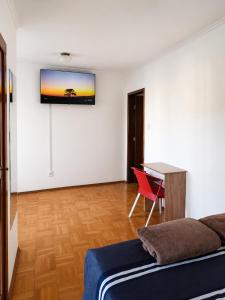 a bedroom with a bed and a desk and a television on the wall at Villa Serena, próx do Aeroporto in Porto Alegre
