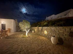 a tree in the middle of a stone wall at night at Maria's Private Space - Mykonos in Ano Mera