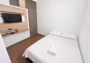 a bedroom with a white bed and a television at Ocean Blue Suites & Hotel Sm in Santa Marta