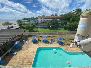 a swimming pool with umbrellas and chairs and the ocean at Antigo hotel murubira in Belém
