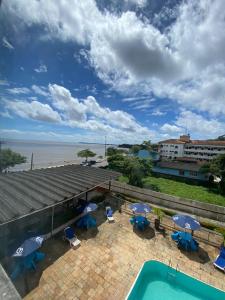 a swimming pool with chairs and umbrellas and the ocean at Antigo hotel murubira in Belém